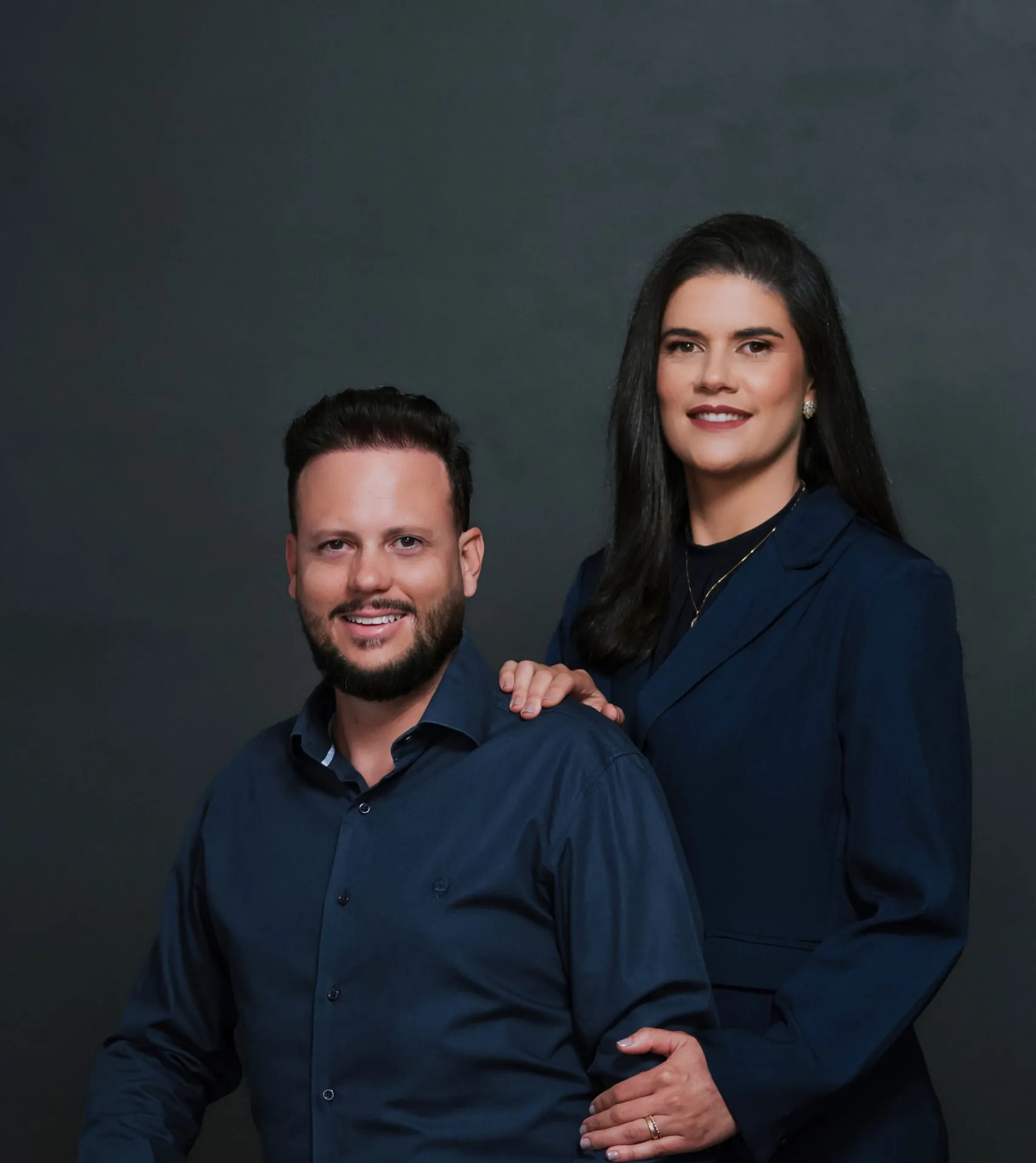 Dois profissionais sorridentes de terno azul.